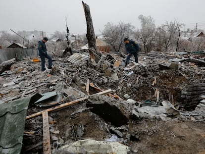 Two officials inspect the ruins of a house destroyed by bombing in the Ukrainian town of Yasynuvata.