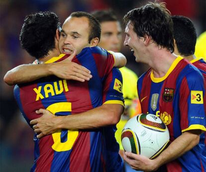 Iniesta and Xavi embrace withe Messi at their side.