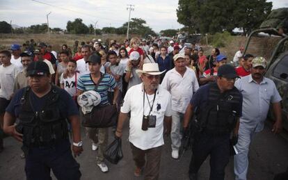 Hip&oacute;lito Mora (in the white hat) turns himself in to authorities.
 