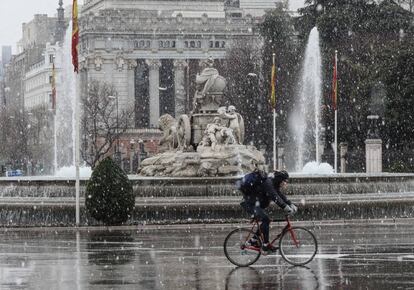 Un ciclista circulaba a las dos de la tarde de ayer junto a la estatua de la Cibeles durante la nevada.