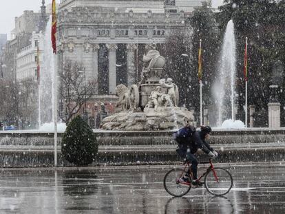 Un ciclista circulaba a las dos de la tarde de ayer junto a la estatua de la Cibeles durante la nevada.