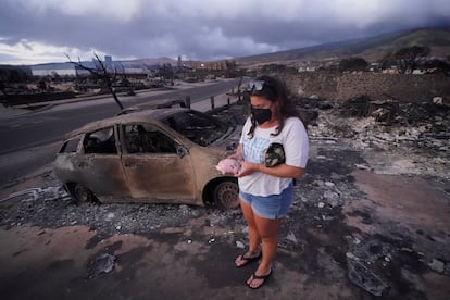 Summer Gerling picks up her piggy bank found in the rubble of her home following the wildfire on Aug. 10, 2023