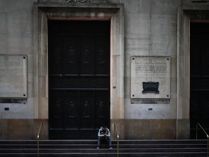 Un hombre espera sentado frente a la puerta de un banco este viernes 22 de mayo, en Buenos Aires.