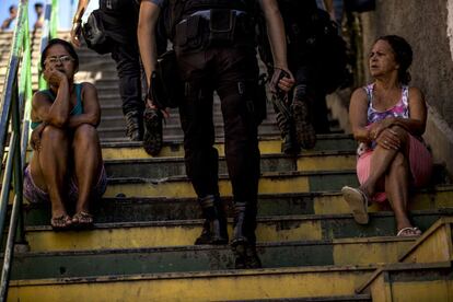 Unos policías armados de la Unidad de Policía Pacificadora patrullan por la favela Providencia mientras dos mujeres les observan. El Anuario Brasileño de Seguridad Pública calcula que, en 2013, la policía fue señalada como responsable de la muerte de 2.212 ciudadanos (seis personas diarias), 416 de ellas en el Estado de Río de Janeiro.