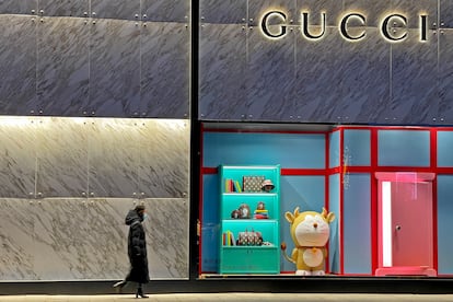 Una mujer pasea frente a una 'boutique' de Gucci en Pekín este mes de enero. Una figura de Doraemon decora el escaparate.