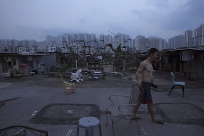 Homem no exterior de seu barraco ilegal construído numa laje, perto de um conjunto habitacional.