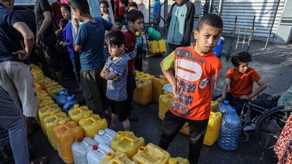 Unos niños palestinos hacen cola en un punto de reparto de agua potable en Rafah (Gaza), este martes.