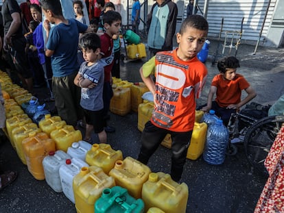 Unos niños palestinos hacen cola en un punto de reparto de agua potable en Rafah (Gaza), este martes.