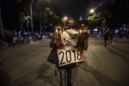 Una mujer camina celebrando el triunfo de López Obrador sobre la avenida Juárez. 
