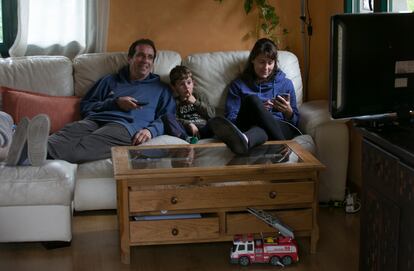 Una familia ve la televisión en el salón de su casa.