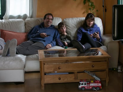 Una familia ve la televisión en el salón de su casa.