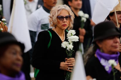 Una mujer sostiene flores blancas durante el acto en la Plaza de Bolívar.