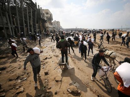 Decenas de palestinos cargan con sacos de harina este lunes en Ciudad de Gaza.