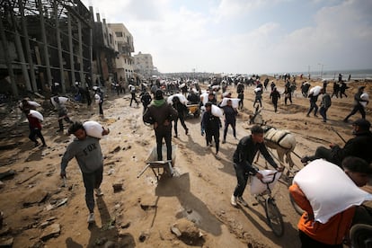 Decenas de palestinos cargan con sacos de harina este lunes en Ciudad de Gaza.