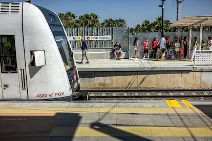 Viajeros en la estación de Paiporta, bajo la escasa sombra en el andén en dirección a Torrent.