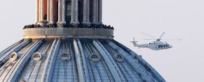 Un grupo de personas en la Basílica de San Pedro miran el helicóptero que llevará al papa Benedicto XVI a su retiro en Castel Gandolfo, donde se hará efectiva la renuncia a su Pontificado.