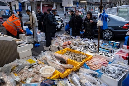 Gente en un puesto de pescado del mercado Whitechapel en High Street, Londres (Inglaterra). 