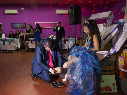 Bernardo Zapata helps his daughter Aleja into high-heeled sandals at her quinceañera party in Madrid.
