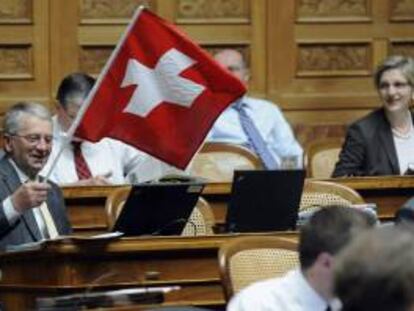 El diputado Walter Müller, del Partido Radical (PRD), ondea una bandera suiza durante el debate sobre el traspaso de datos de clientes estadounidenses del banco suizo UBS, en Berna (Suiza). EFE/Archivo