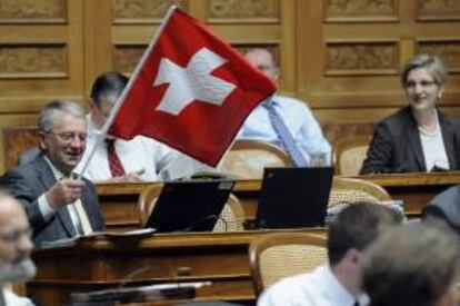 El diputado Walter Müller, del Partido Radical (PRD), ondea una bandera suiza durante el debate sobre el traspaso de datos de clientes estadounidenses del banco suizo UBS, en Berna (Suiza). EFE/Archivo