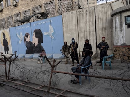 Un grupo de talibanes monta guardia en Kabul ante un cartel que representa a una mujer y a una niña.