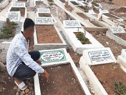 Un joven marroquí señala la tumba del sudanés Mohamed Alí Adam B., muerto en el salto a la valla de Melilla hace un año, el sábado en el cementerio de Sidi Salem de Nador (Marruecos).