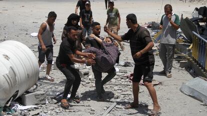 Unos hombres trasladan a los heridos después de un ataque israelí a un centro de la agencia para refugiados palestinos de la ONU (UNRWA), este domingo.