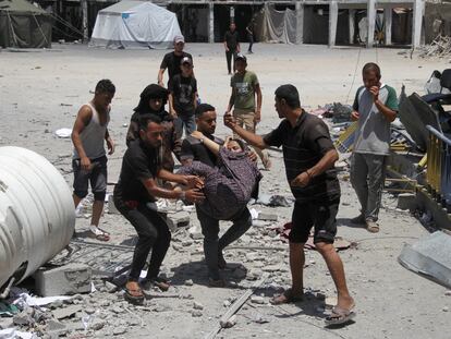 Unos hombres trasladan a los heridos después de un ataque israelí a un centro de la agencia para refugiados palestinos de la ONU (UNRWA), este domingo.