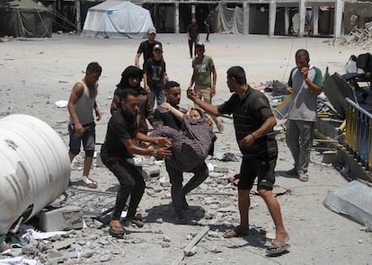 Unos hombres trasladan a los heridos después de un ataque israelí a un centro de la agencia para refugiados palestinos de la ONU (UNRWA), este domingo.