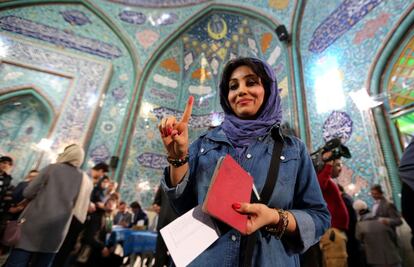 Una mujer iraní muestra su dedo entintado después de emitir su voto en un colegio electoral de Teherán.