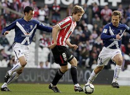 Llorente pasa el balón entre dos jugadores rivales.