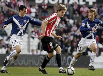 Llorente pasa el balón entre dos jugadores rivales.