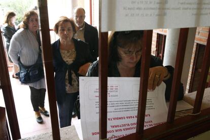 Varias personas consultan las listas antes de ejercer su derecho al voto en el Instituto P&eacute;rez Gald&oacute;s de Madrid.