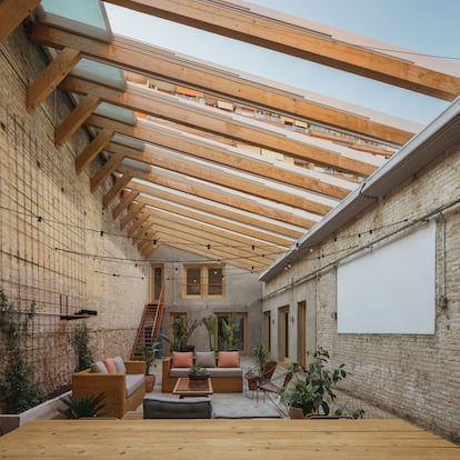El patio de la vivienda se cubre mediante un sistema prefabricado de carriles de vidrio laminado retráctiles que permiten abrir o cerrar el espacio según las necesidades climáticas.