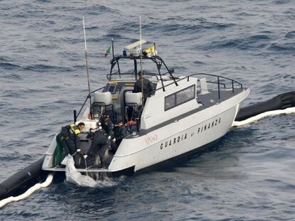 Una patrulla de policía sube a bordo un cadáver recuperado del crucero.