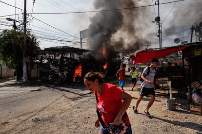 Personas corren al lado de un camión que fue incendiado en Acapulco, Guerrero.