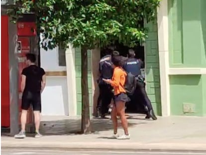 Varios agentes de la Policía Nacional empujan a un hombre al interior de un portal durante una intervención este sábado en Valencia.