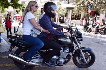 El exministro de Finanzas griego Yanis Varoufakis conduce su motocicleta por una calle de Atenas llevando en la parte trasera a su mujer Danae Stratou.