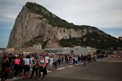 Peatones cruzan la pista en el aeropuerto de Gibraltar, con el pe&ntilde;&oacute;n al fondo.