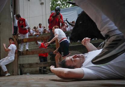 Un corredor cae ante uno de los toros en la entrada al callejón que da acceso a la Plaza de Toros de Pamplona. 
