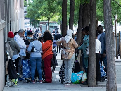 Varias personas esperando para recoger alimentos en la Fundación Karibu (Madrid).