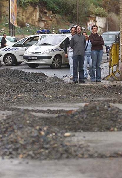 Unos jóvenes observan las piedras arrastradas por la lluvia ayer hasta la plaza de la Merced, en Huelva.