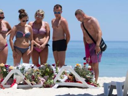 Un grupo de turistas contemplan las flores depositadas en la playa tras el ataque en junio a un hotel en Susa (T&uacute;nez). &nbsp;