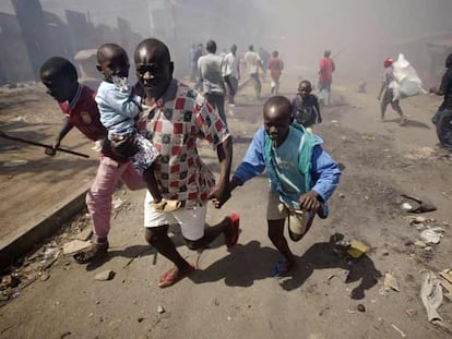 Un hombre conduce ayer a un grupo de niños fuera del suburbio de Mathare, en Nairobi, tras varios días de violencia.