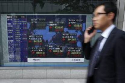 Un viandante pasa delante de una pantalla que muestra varios valores bursátiles en una calle de Tokio. EFE/Archivo
