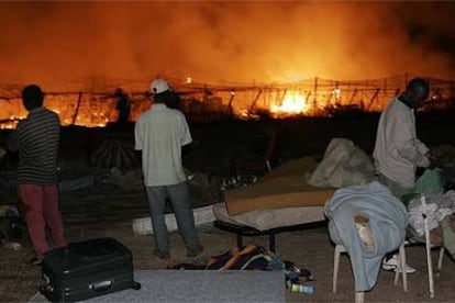 Varios inmigrantes observan el incendio en el invernadero del pueblo almeriense de San Isidro de Níjar.