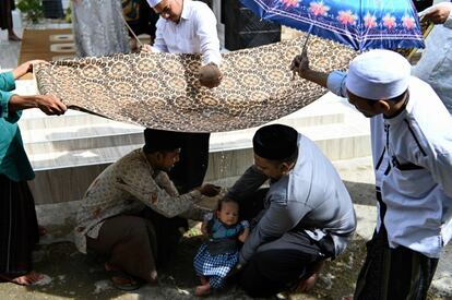 La gente reza por un bebé recién nacido durante el 'aqiqah', una tradición indonesia para dar la bienvenida a un bebé a una familia, en Banda Aceh, Indonesia.