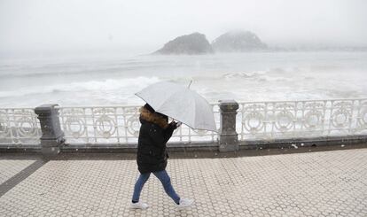 Una dona es protegeix amb una paraigua a la platja d'Ondarreta.