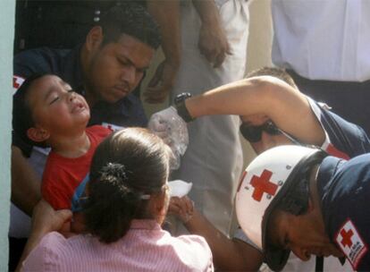 Socorristas de Cruz Roja evacuan a un niño de la guardería.