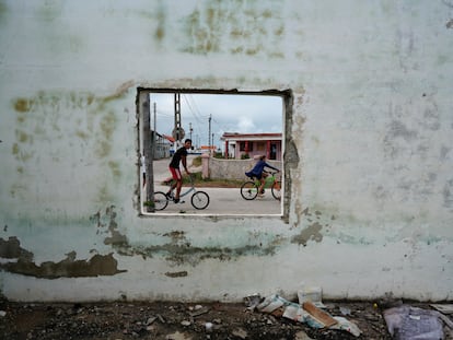 Niños en bicicleta pasan frente a un edificio abandonado en Isabela de Sagua, Cuba el 28 de enero 2023
